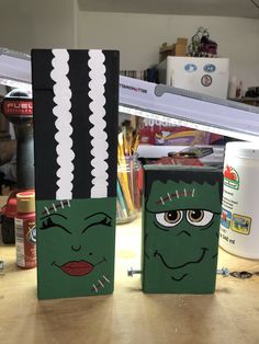 two boxes with faces painted on them sitting on a table in front of a mirror