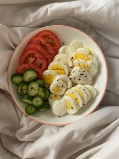 a white plate topped with sliced up tomatoes and hard boiled eggs next to cucumbers