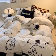 an unmade bed with cartoon drawings on it and pillows in the shape of animals