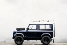 a blue land rover vehicle parked in front of a white wall