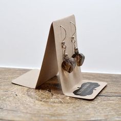 a pair of heart shaped earrings sitting on top of a wooden table next to a card