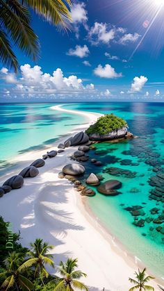 the beach is surrounded by palm trees and clear blue water with rocks in the foreground