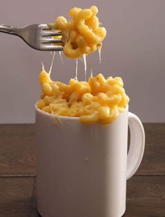 a fork is lifting some macaroni out of a cup