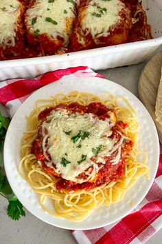 a white plate topped with spaghetti next to a casserole dish filled with meatballs