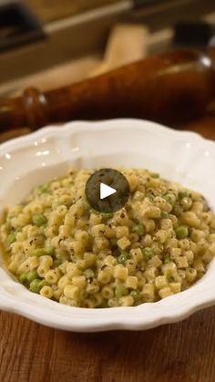 a white bowl filled with macaroni and peas