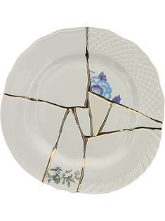 a broken plate with blue flowers and gold strips on the rim is shown in front of a white background