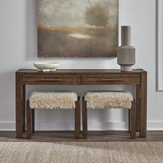 two stools in front of a table with a painting on the wall