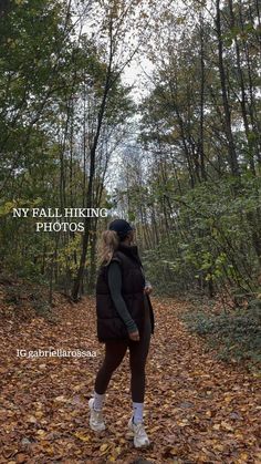 a woman walking down a leaf covered path in the woods with her back to the camera