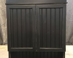 a tall black cabinet with two doors