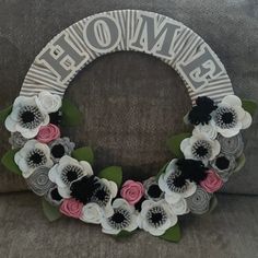 a wreath made out of flowers sitting on top of a gray couch next to a pillow