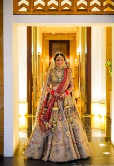 a woman in a bridal gown and jewelry stands outside the entrance to a building