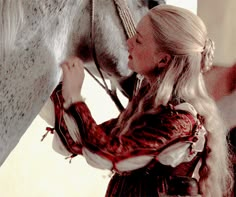 a woman standing next to a white horse