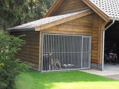 a dog is standing behind a fence in front of a garage