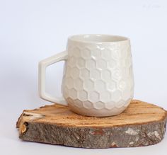 a white coffee mug sitting on top of a piece of wood