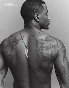 the back of a man with tattoos on his chest and shoulder, looking at something