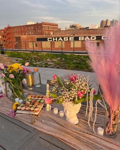 a table topped with lots of food and vases filled with flowers next to each other