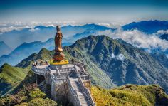 a statue on top of a mountain with mountains in the background