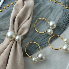 three pairs of pearl earrings sitting on top of a white cloth next to a pair of gold hoop earrings