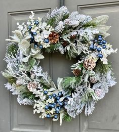 a christmas wreath with pine cones, berries and greenery on the front door is displayed