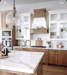 a kitchen with wooden cabinets and white marble counter tops, an island in the middle