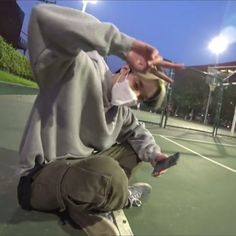 a man sitting on top of a tennis court holding his hand up to his face