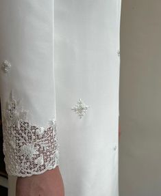 a woman's white shirt with lace trimmings and buttons on the sleeves