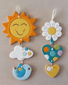 three sun, flower and bird shaped cookies hanging from strings on a counter top with string