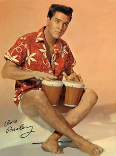 a man sitting on the ground holding two drums