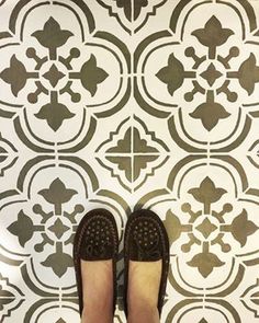 someone's feet are standing in front of a wall with black and white tiles