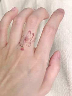 a woman's hand with a small tattoo on her left thumb and a pink flower in the middle