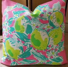 a pink and green pillow sitting on top of a chair