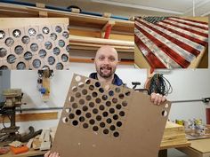 a man holding up a cardboard cutout with an american flag in the back ground