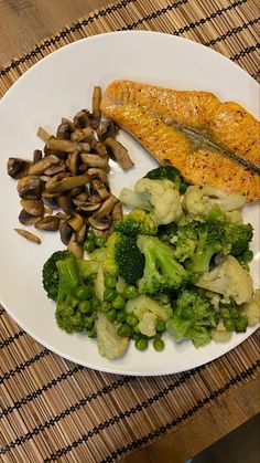 a white plate topped with fish, broccoli and mushrooms