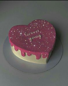 a heart shaped cake with pink icing and sprinkles on the top