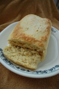 a piece of bread sitting on top of a white and blue plate next to a brown cloth