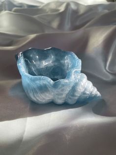 a blue glass bowl sitting on top of a white cloth covered tablecloth with folds in the fabric