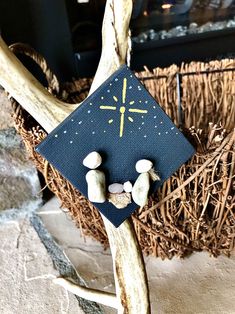 two small rocks sitting on top of a piece of wood with a cross in the middle