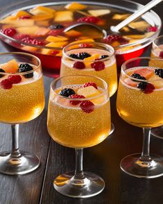 four glasses filled with liquid and topped with fruit