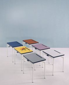 four tables with different colored tops and white legs, all on one end in the same color