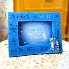 a blue frame with the words a whole new world and a castle on it sitting on a table