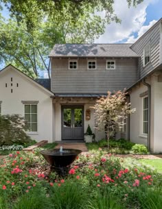 a house with flowers in front of it and a water fountain on the side walk