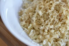 a white bowl filled with rice on top of a wooden table