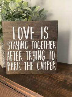 a wooden sign that says love is staying together after trying to park the camper