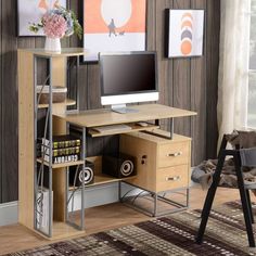 a desk with a computer on it in front of a wall mounted art work area