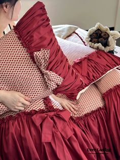 a woman laying on top of a bed wearing a red dress with white polka dots