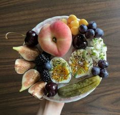 a person holding a plate with fruits and vegetables on it