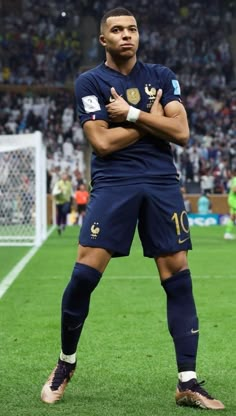 a man standing on top of a soccer field with his arms crossed in front of him