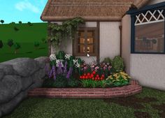 a small house with flowers in front of it and a rock wall next to it