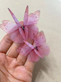 two pink butterflies sitting on the palm of someone's hand