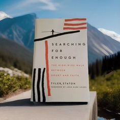 a book sitting on top of a white table next to a forest filled with trees